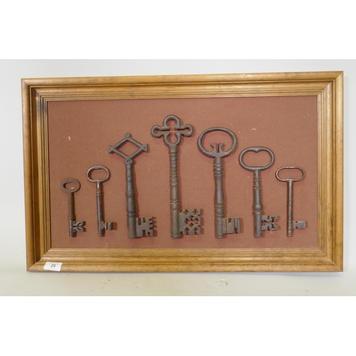 25 - A collection of seven antique keys, mounted on a pine frame, largest key 28cm long