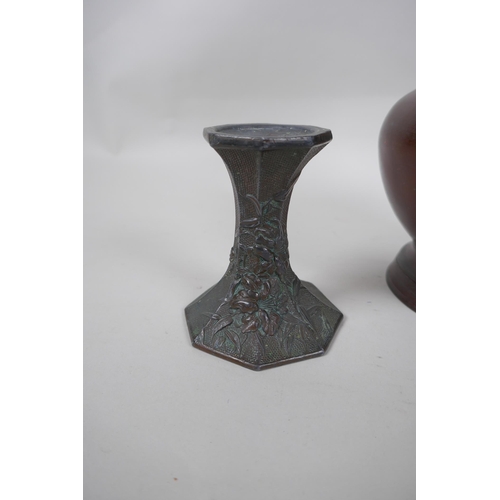 257 - A pair of early C20th Japanese bronze candlesticks of hexagonal waisted form, with raised floral dec... 