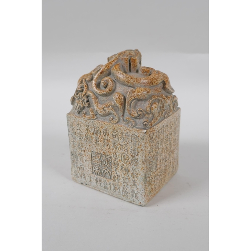 263 - A reconstituted stone seal with dragon decoration to top and allover character inscription, 13cm hig... 