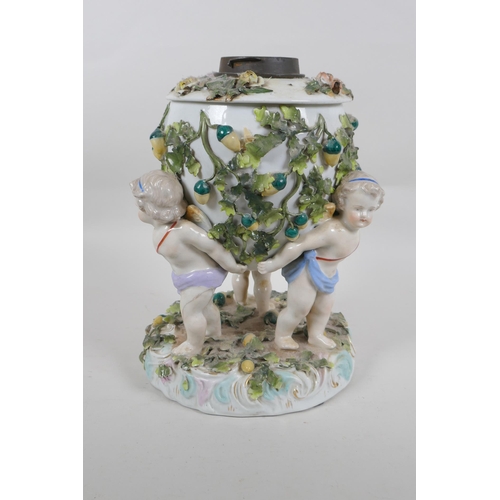 264 - An antique continental porcelain oil lamp converted to electricity, decorated with three winged putt... 