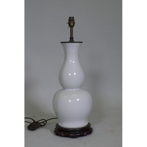 40 - A white glazed porcelain table lamp in the form of an oriental vase, with brass mount and carved woo... 