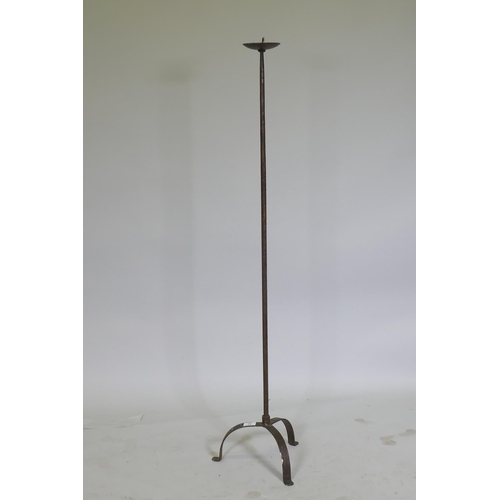 42 - A wrought iron floor standing pricket candlestick on tripod supports, 128cm high