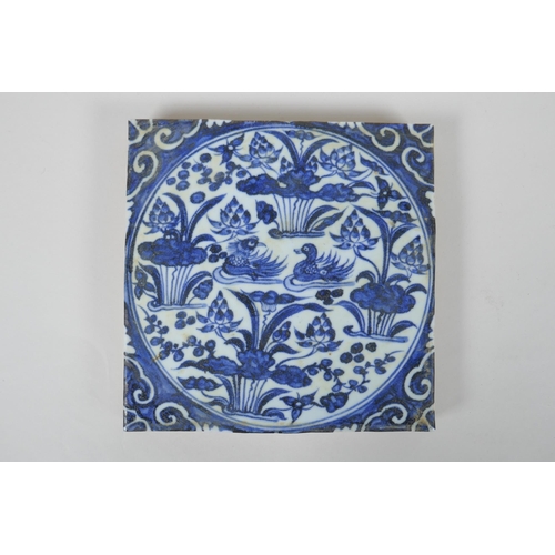 43 - A Chinese blue and white porcelain temple tile decorated with waterfowl in a lotus pond, 20 x 20cm