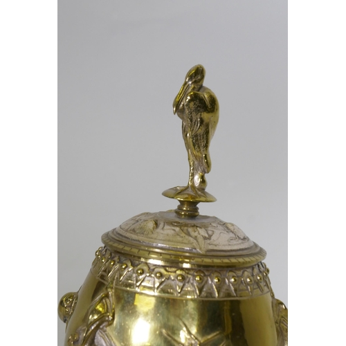 644 - After August Cain, silver and gilt plated urn and cover, with stork finial, with raised decoration o... 