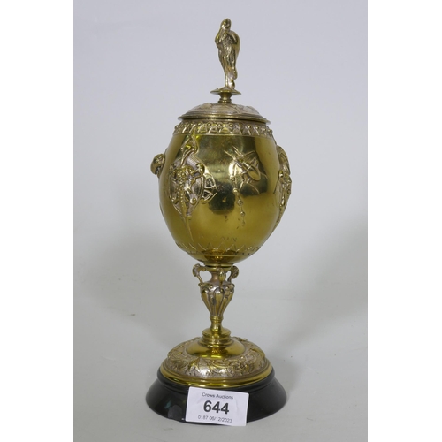 658 - After August Cain, silver and gilt plated urn and cover, with stork finial, with raised decoration o... 