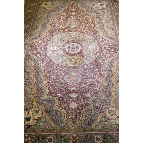 1105 - A Turkish Hereke wool carpet with central design on a faded terracotta field, with blue/grey borders... 