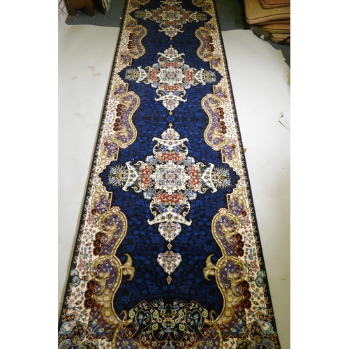 1102 - An Iranian fine woven runner with floral medallion design on a deep blue field, 100x  410cm