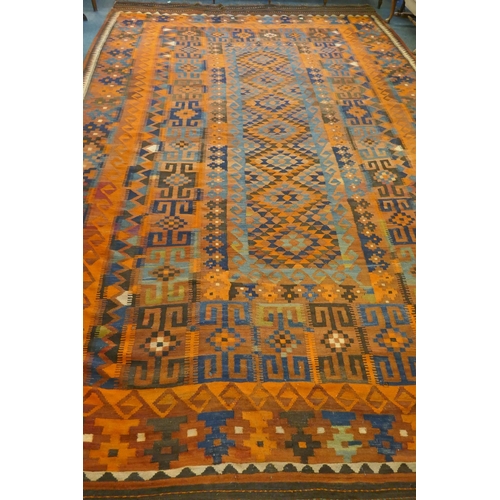 1039 - A large Middle Eastern orange and burgundy ground hand woven kilim carpet, 310 x 500cm