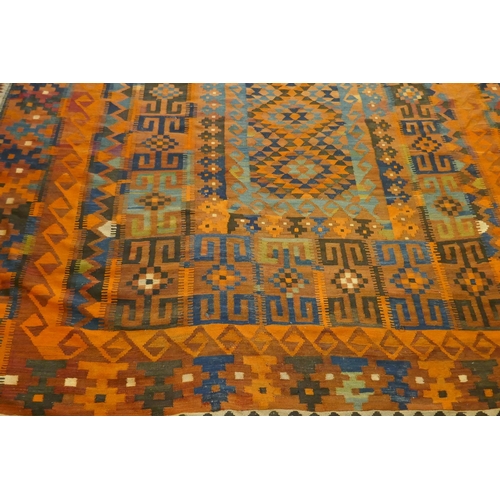 1039 - A large Middle Eastern orange and burgundy ground hand woven kilim carpet, 310 x 500cm