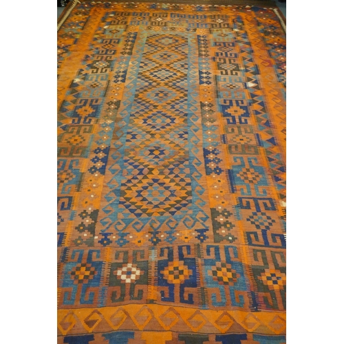 1039 - A large Middle Eastern orange and burgundy ground hand woven kilim carpet, 310 x 500cm