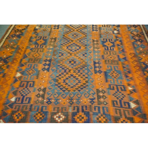 1039 - A large Middle Eastern orange and burgundy ground hand woven kilim carpet, 310 x 500cm