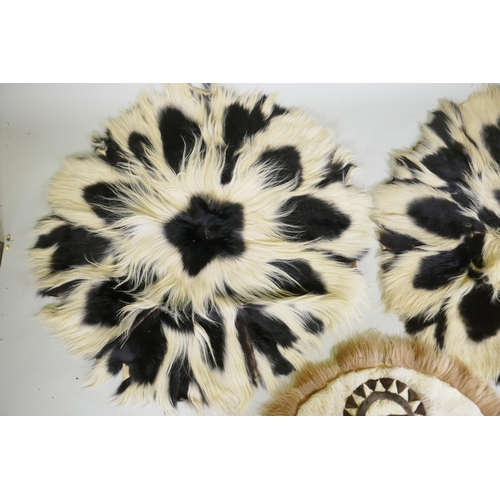 1050 - A pair of circular animal fur rugs, and another with lion design, largest 120cm diameter