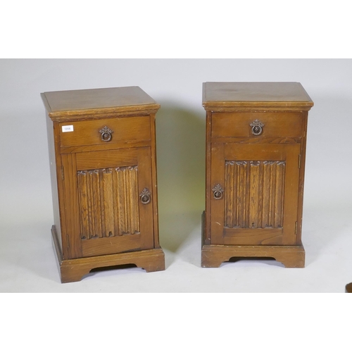 1056 - A pair of 'Maple' oak bedside chests, with single drawer over a cupboard, with linen fold panel, rai... 