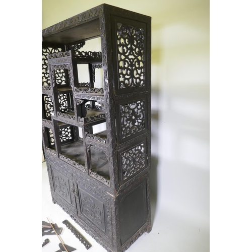 1062 - A C19th Chinese hardwood display cabinet in two sections, the upper with carved and pierced sides an... 