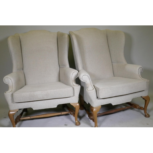 1096 - A good pair of Georgian style high back wing armchairs with wide seats, raised on walnut cabriole su... 