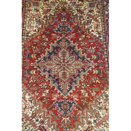 1123 - An antique Persian red and cream ground Heriz full pile carpet with black borders, 210 x 296cm