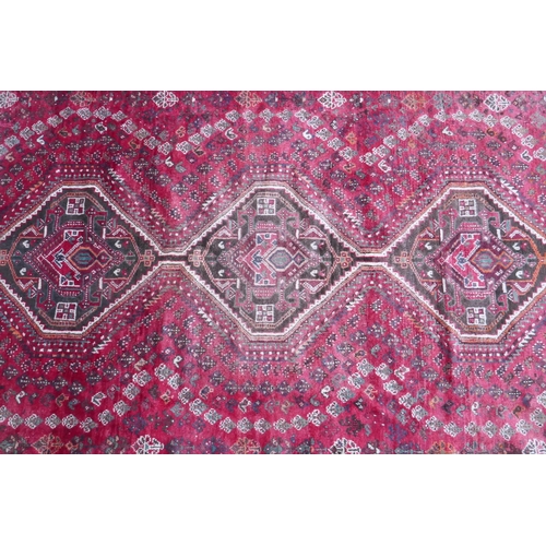 1128 - A Persian washed red ground full pile Qashqai tribal carpet, 216 x 294cm