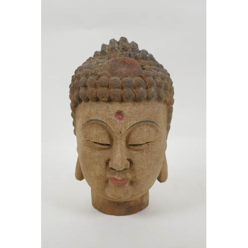 125 - A Chinese carved, painted and distressed wood Buddha head, 21cm high