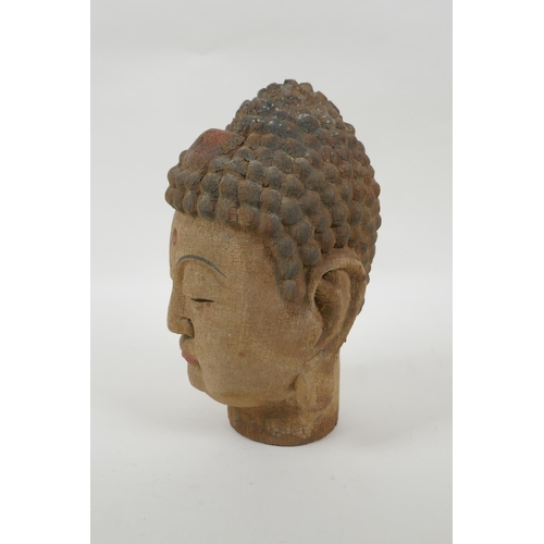 125 - A Chinese carved, painted and distressed wood Buddha head, 21cm high