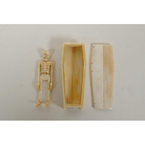 134 - A bone coffin opening to reveal a skeleton with articulated limbs, 12cm long