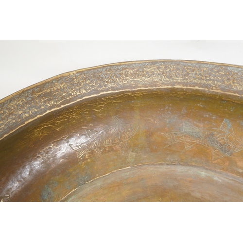 147 - An antique Islamic gilt brass bowl with central boss and chased fish decoration, 46cm diameter