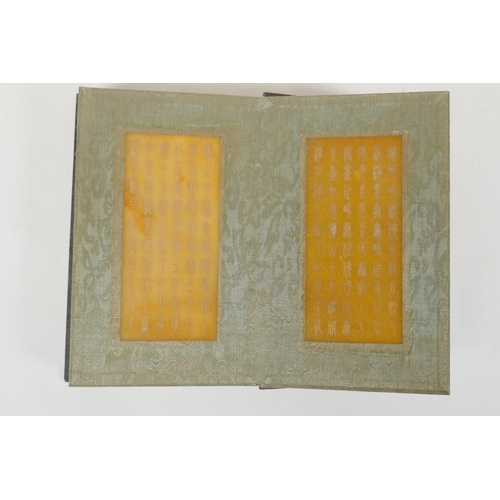 166 - A Chinese wood and silk bound book containing amber hardstone tablets with chased and gilt character... 