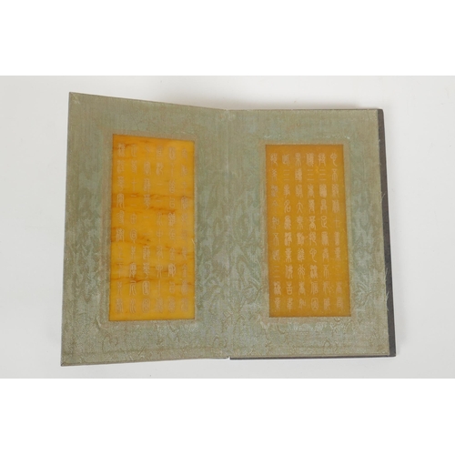 166 - A Chinese wood and silk bound book containing amber hardstone tablets with chased and gilt character... 