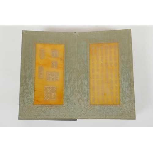 166 - A Chinese wood and silk bound book containing amber hardstone tablets with chased and gilt character... 