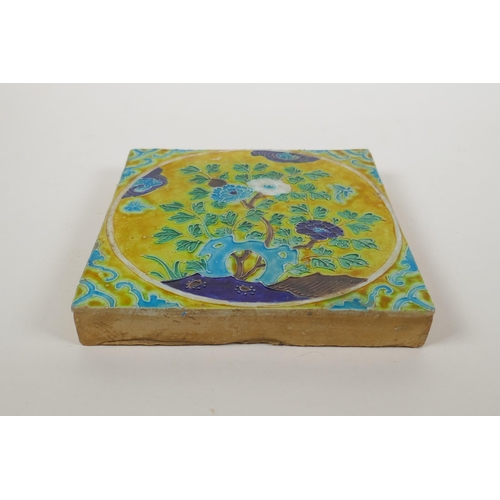 203 - A Chinese yellow ground porcelain temple tile with fahua decoration of flowers, 20 x 20cm