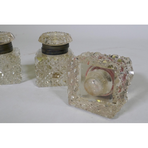 22 - A set of three large Victorian cut glass inkwells with brass mounts, 11cm high