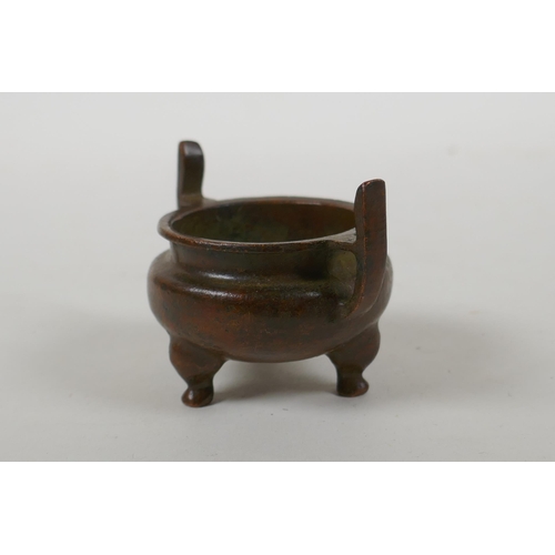 228 - A Chinese bronze two handled censer raised on tripod supports, Xuan character mark to base, 5cm diam... 