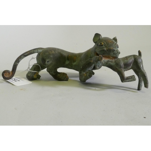 253 - An Eastern bronze figure of a lion with prey, 20 x 7cm high