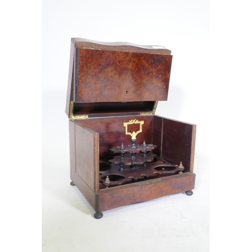 34 - A C19th amboyna and ebony serpentine front decanter case, the lift up top and fold out sides opening... 