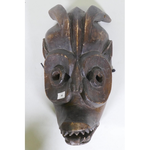 44 - An African tribal carved wood horned mask with hinged jaw, 50cm long, AF minor loss and break