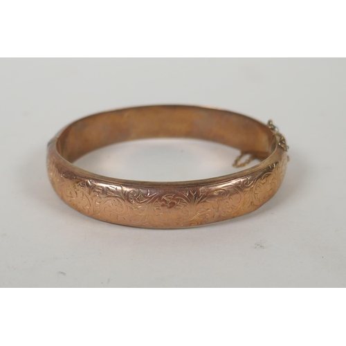 605 - A 9ct gold bangle with scrolling decoration and inscription, 6 x 5.5cm, 14.9g