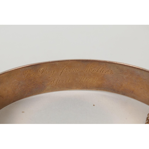 605 - A 9ct gold bangle with scrolling decoration and inscription, 6 x 5.5cm, 14.9g