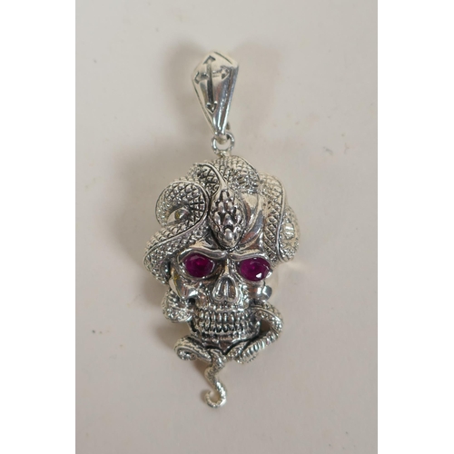 631 - A white metal pendant in the form of a skull entwined with a snake, 6cm drop