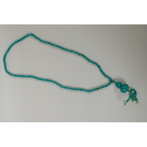 634 - An oriental turquoise style bead necklace with double gourd feature bead, 84cm long