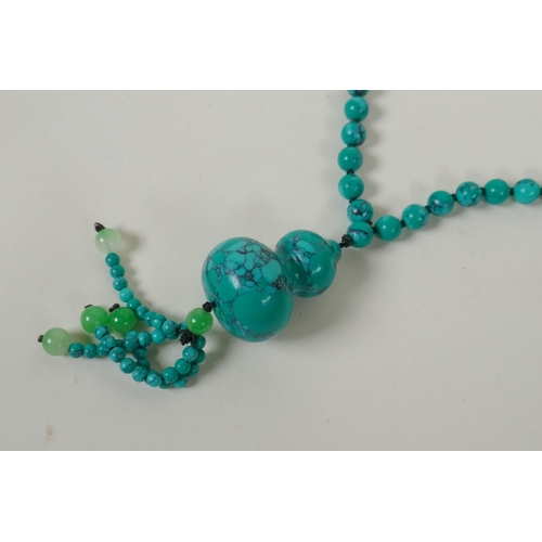 634 - An oriental turquoise style bead necklace with double gourd feature bead, 84cm long