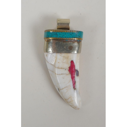 642 - A Tibetan white metal mounted tooth pendant with enamel details, 7cm