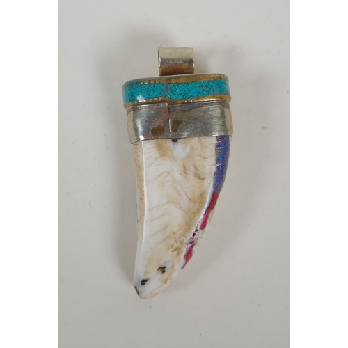 642 - A Tibetan white metal mounted tooth pendant with enamel details, 7cm