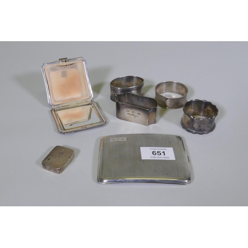 651 - A hallmarked silver cigarette case, compact, pill box and four napkin rings, 259g