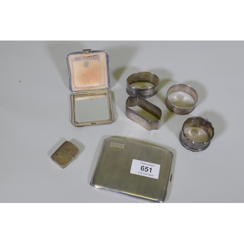 651 - A hallmarked silver cigarette case, compact, pill box and four napkin rings, 259g