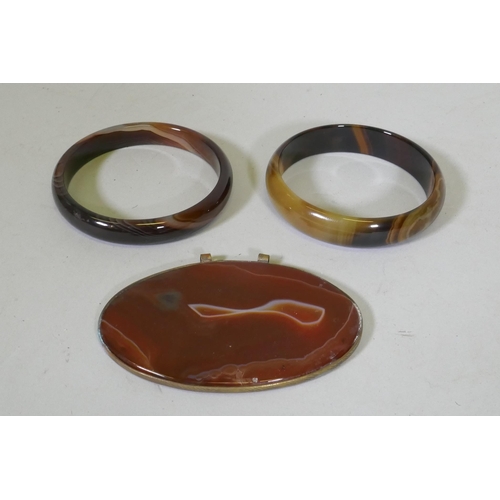 673 - A pair of agate bangles, 16.3cm internal diameter, and an agate pendant in metal mount