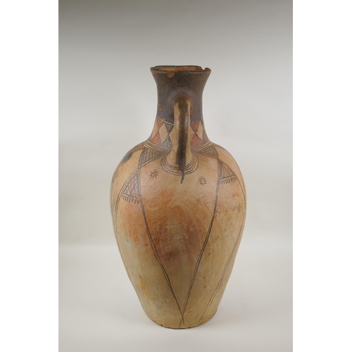 84 - An antique North African terracotta amphora with two handles and hand painted design, AF, 63cm high