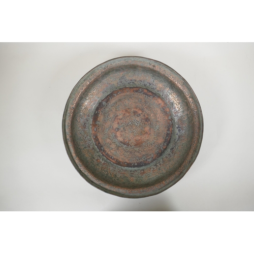 85 - An antique Islamic copper dish with chased script and floral decoration, 34cm diameter