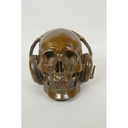 87 - A decorative filled bronze skull wearing headphones, 16cm high