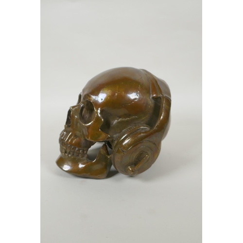 87 - A decorative filled bronze skull wearing headphones, 16cm high