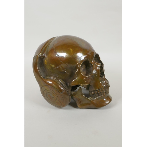 87 - A decorative filled bronze skull wearing headphones, 16cm high