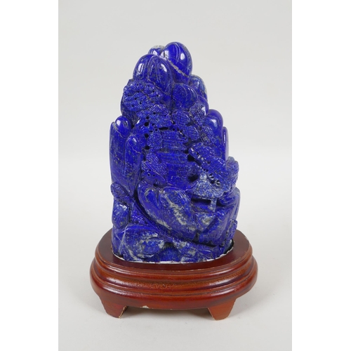 97 - A large Chinese lapis lazuli carving of a mountain side village, on a wood stand, 22cm high